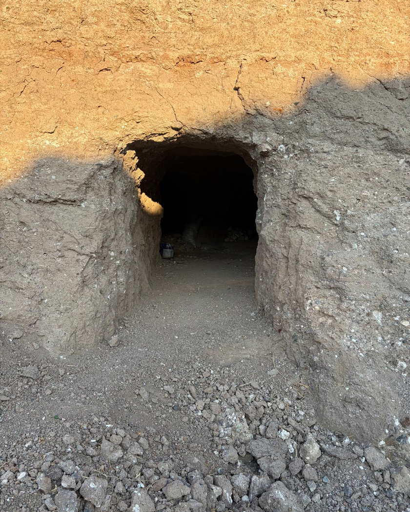 Toprak duvarda açılmış, insan boyuna yakın yükseklikte kemerli bir galeri ağzı; içerisi karanlık.