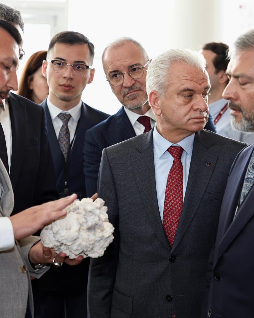 Sergi alanında, elinde beyaz bir lületaşı yumrusu tutan bir kişi ve çevresinde onu dinleyen bir grup.
