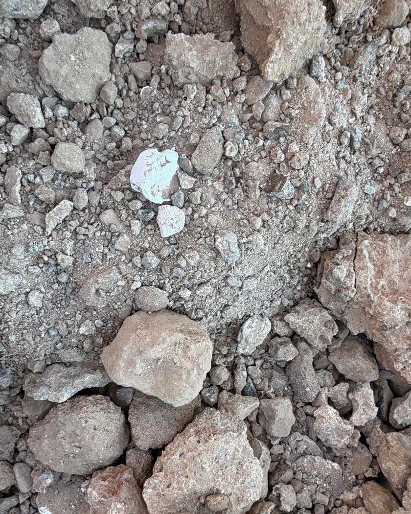 Kırılmış taş ve toprak yığınının içinde göze çarpan, parlak beyaz bir taş parçası.