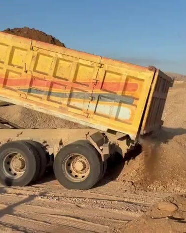 Damperli kamyonun kasasını kaldırarak malzemeyi sahaya boşaltması ve boşaltılan malzemenin yakın planı.